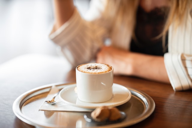 woman sit with cappucino on the table.