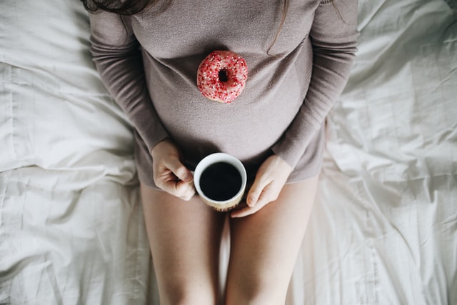 Woman pregnant holding cup of coffee.