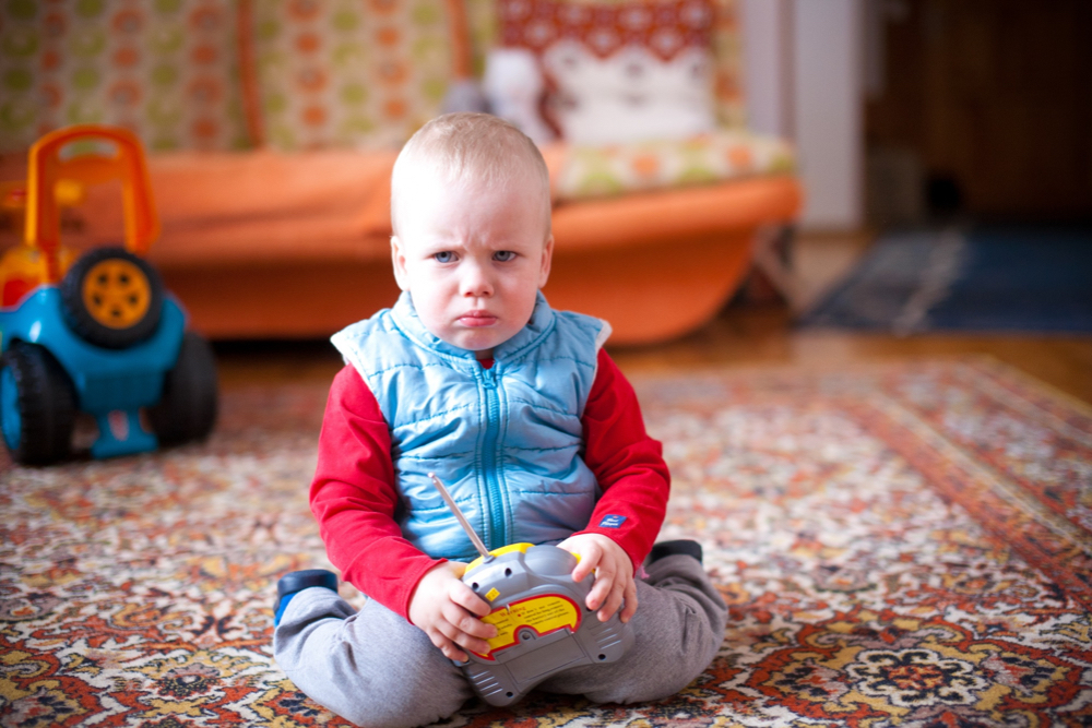 little boy feeling grumpy with his toy