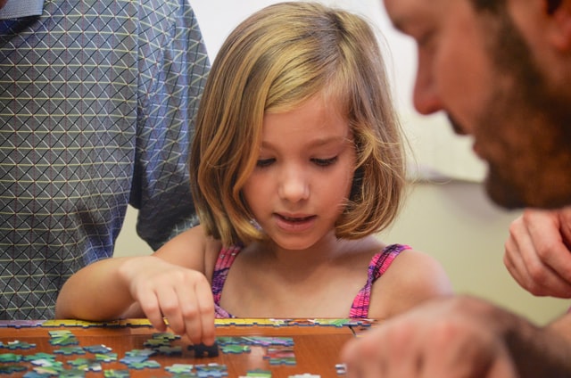 a young girl playing puzzle with his dad
