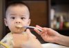 baby boy eating from spoon by his mom